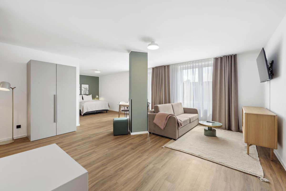 Une chambre d’hôtel moderne équipée d’un lit, d’un canapé, d’une télévision et d’un bureau.