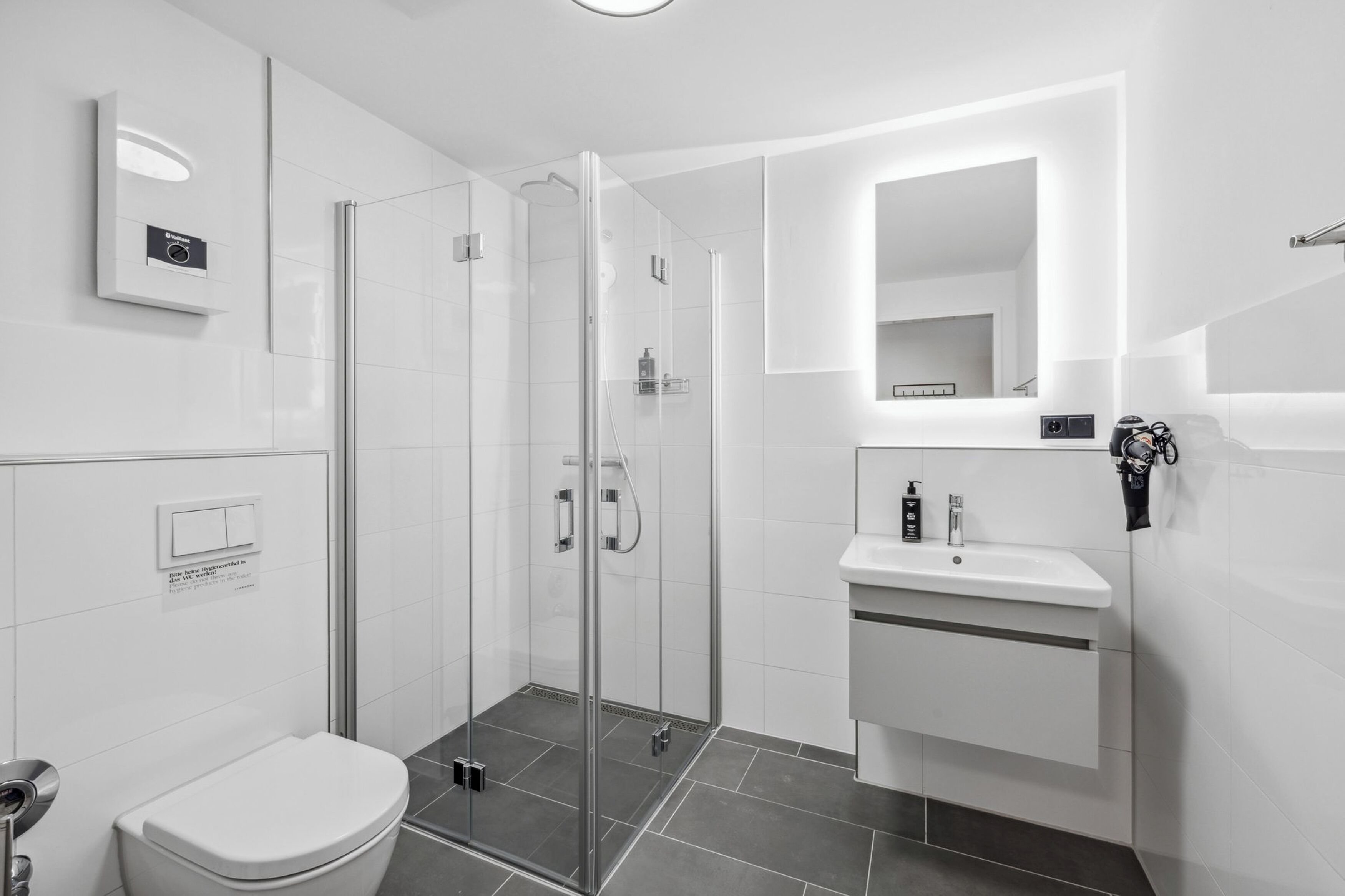 Un bagno moderno con doccia vetrata, lavandino bianco e WC.