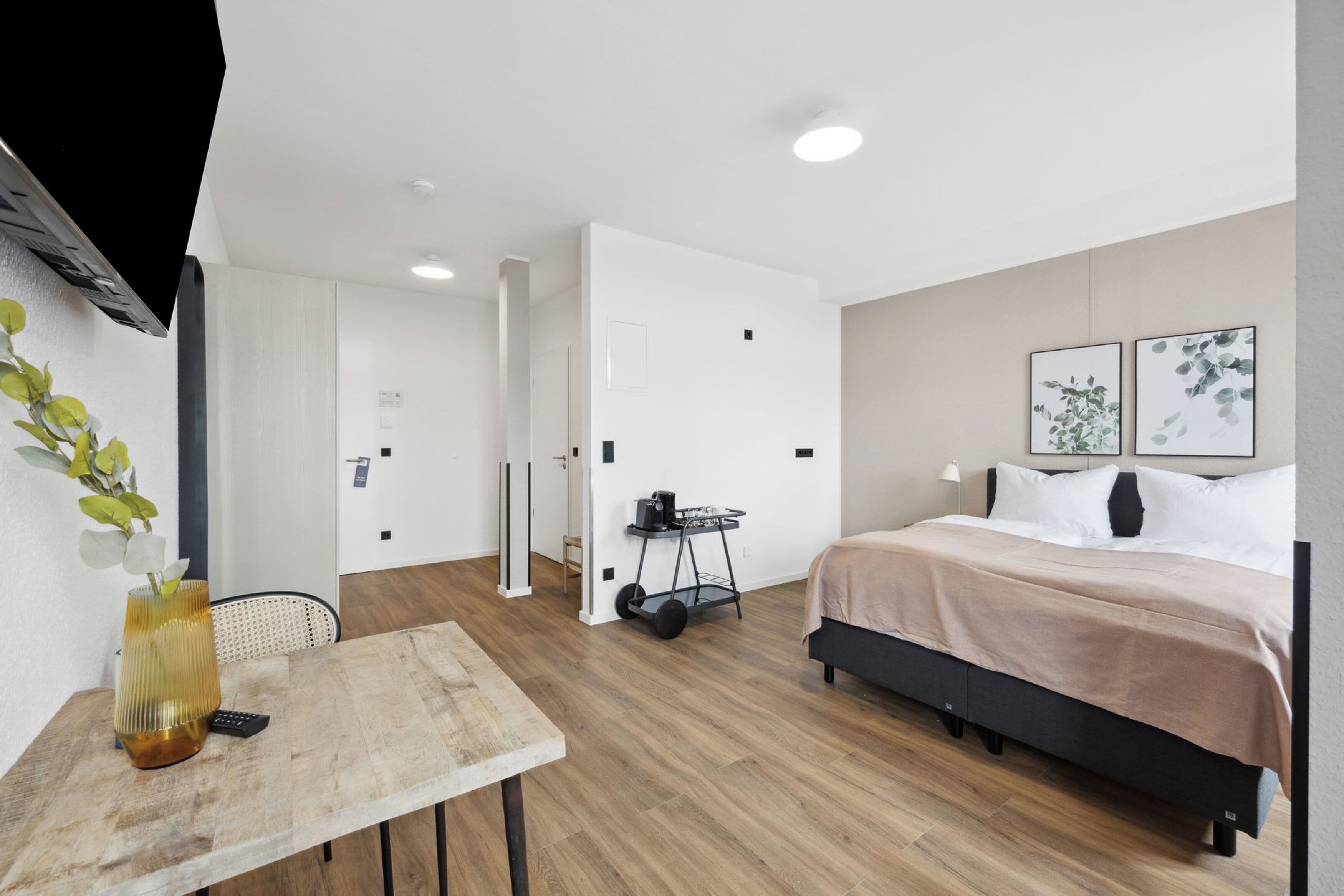 Et moderne hotelværelse med seng, sengebord og et lille skrivebord.