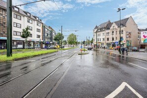 Experience the vibrant city atmosphere with a tram line running along the street, lined with local businesses and shops.