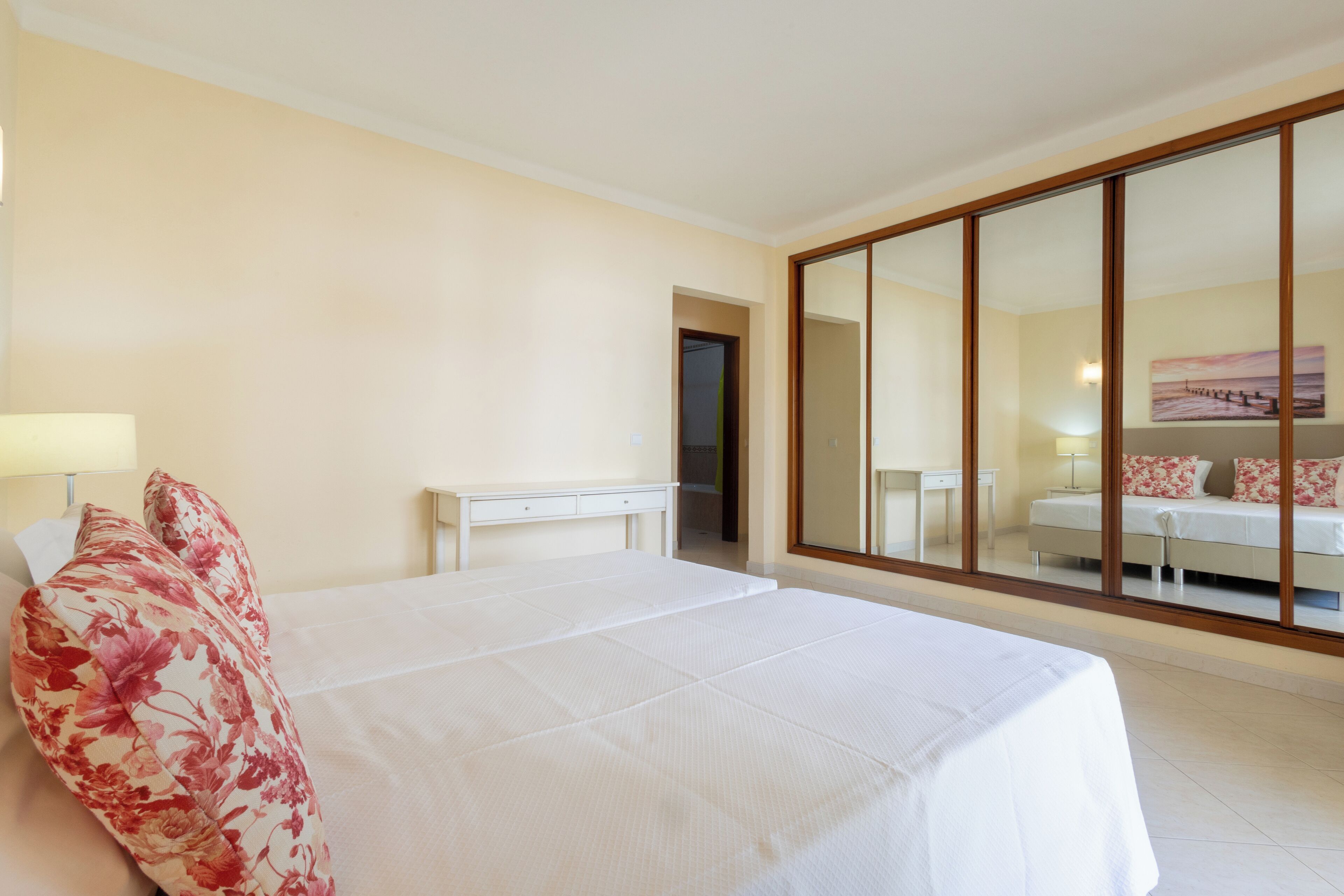 A hotel room with a large bed, a desk, a chair, and a mirror.
