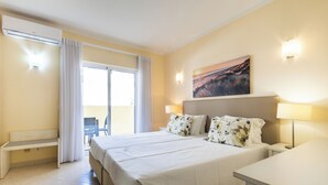 A hotel room with a bed, bedside tables, a desk, and a view of the outdoors. - Vila Marachique - Torralvor (Portimão)