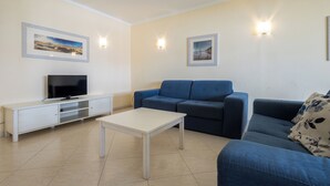 A living room with a TV, a sofa, a coffee table, and two wall-mounted lights. - Vila Marachique - Torralvor (Portimão)