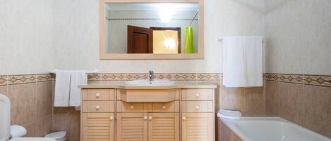 Un baño con inodoro, lavamanos, tocador y bañera.