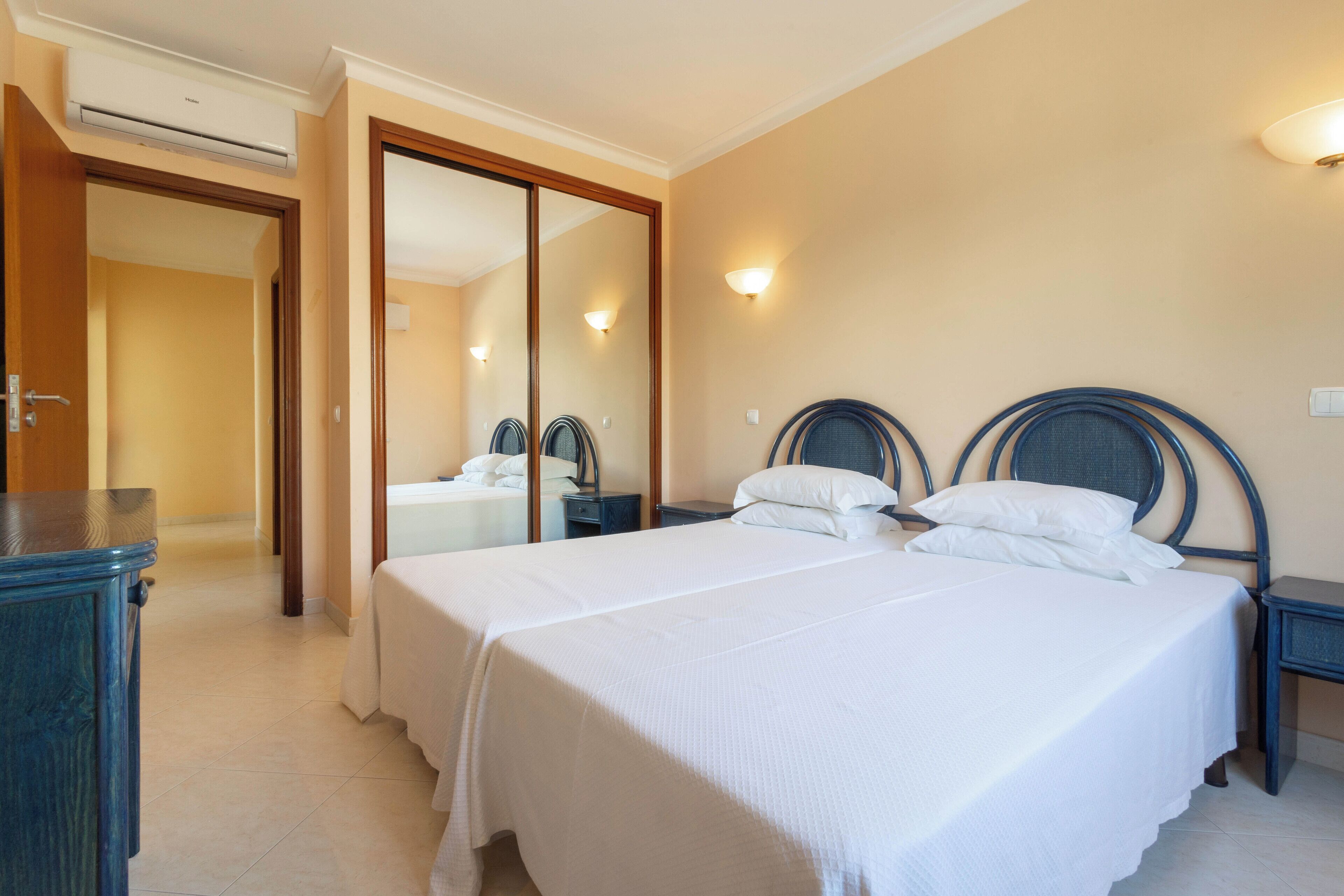 Ein Hotelzimmer mit zwei Betten, einem Schrank, einem Nachttisch und einem Spiegel.