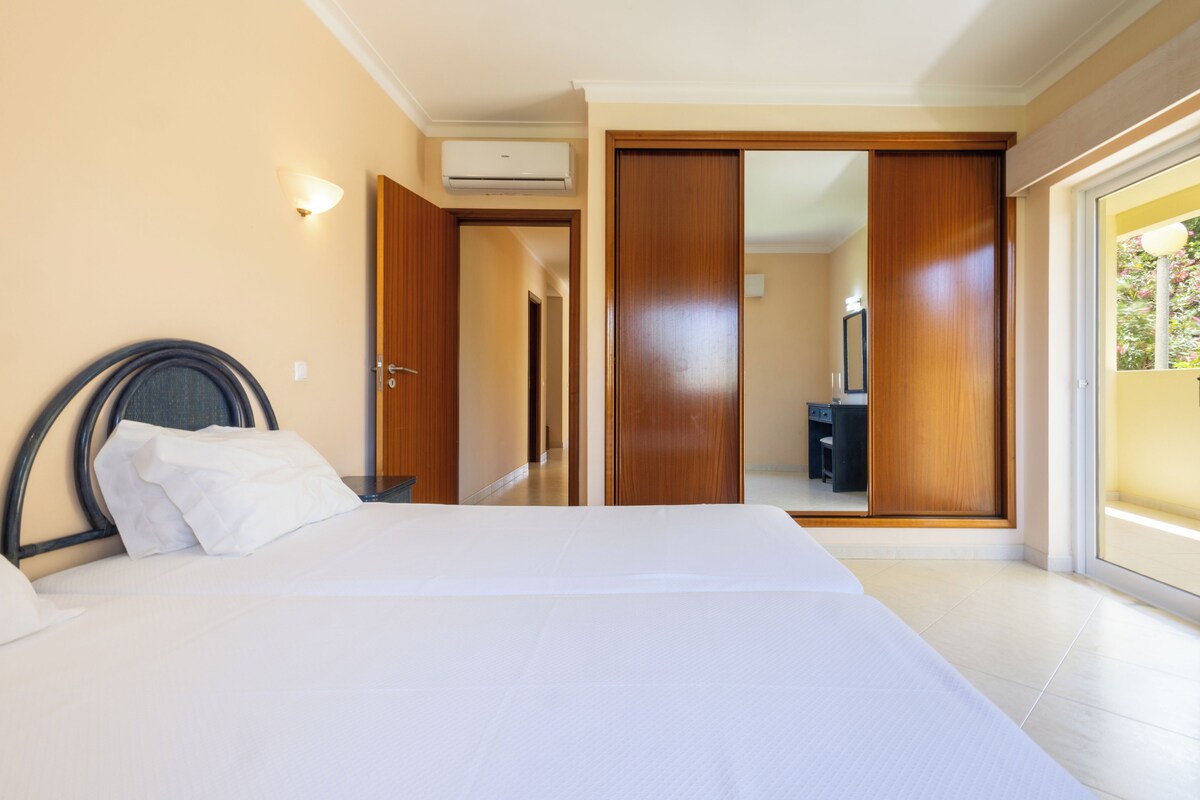 A hotel room with a bed, a wardrobe, and a sliding door leading to a balcony.
