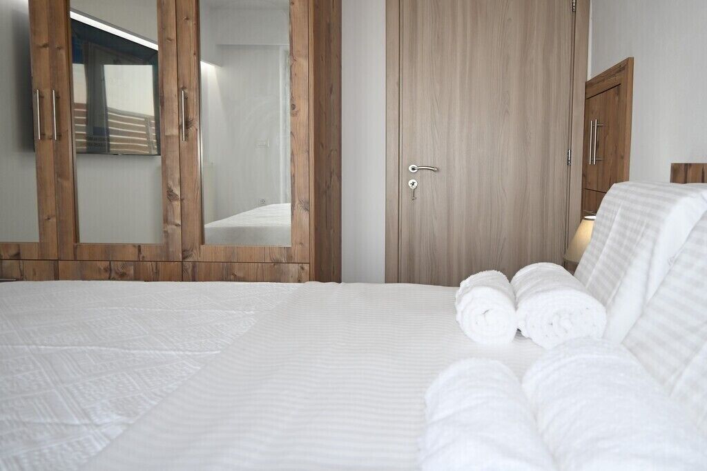 A bedroom with a large bed, wooden wardrobe, and a mirror.