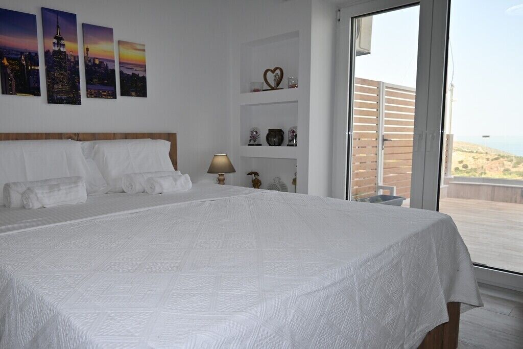 Ein Schlafzimmer mit einem großen Bett, einem Nachttisch, einer Lampe und Blick ins Freie.