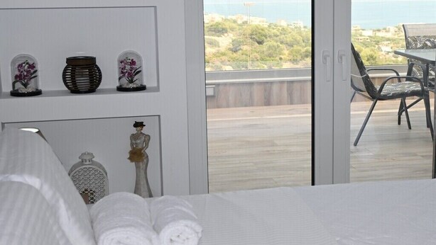 Une chambre à coucher avec un lit, des serviettes pliées, des objets décoratifs et une vue sur l’extérieur.