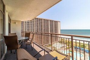 Enjoy the ocean view from this balcony with wicker chairs and a small table.