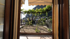 A view from a balcony with a pergola, a gravel area, and a mountain backdrop.
