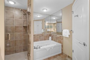 A modern bathroom with a walk-in shower, a freestanding bathtub, and a large mirror.