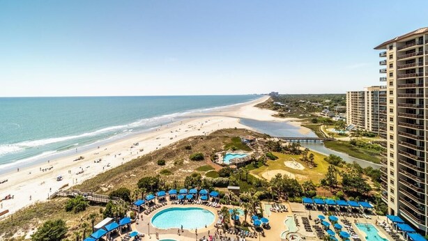 Un complexe hôtelier doté d’une grande piscine, d’une plage et d’un immeuble de grande hauteur.