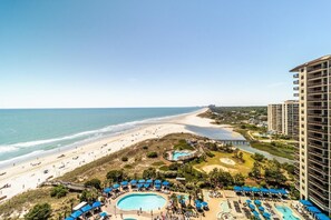 A resort with a large pool area, a beach, and a high-rise building.