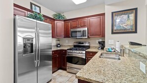 Una cocina moderna con electrodomésticos de acero inoxidable, encimeras de granito y armarios de madera.