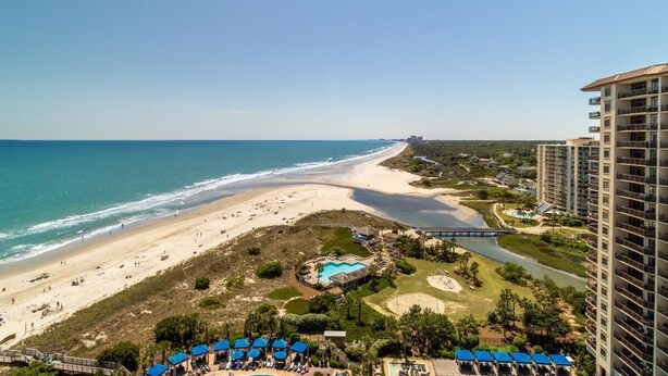 Un hotel costero con vistas a la playa, piscina y campo de golf.