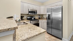 A kitchen with granite countertops, stainless steel appliances, and white cabinetry. - Beachfront Paradise: Spacious 2BR Condo with Views (North Myrtle Beach)