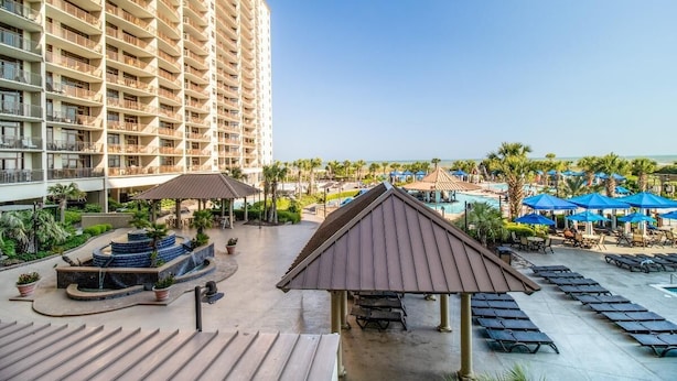 A resort with a large building, a swimming pool, and outdoor seating areas. - Beachfront Paradise: Spacious 2BR Condo with Views (North Myrtle Beach)