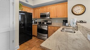 Una cocina con armarios de madera, un refrigerador de acero inoxidable, un microondas, una estufa y un lavamanos.