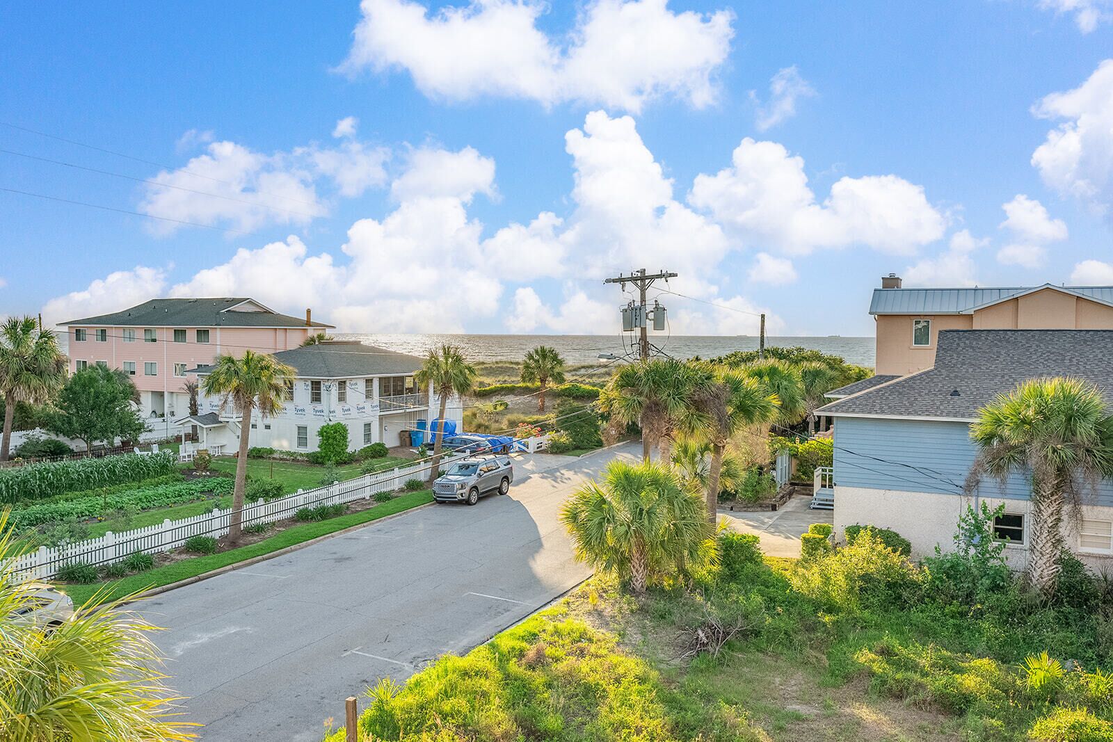 A coastal residential area with houses, a road, and a view of the ocean.