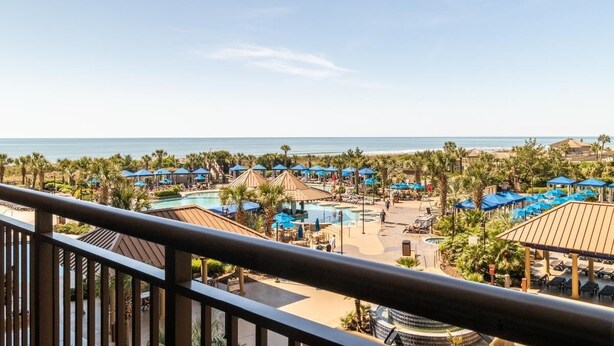 A resort with a pool, beach, and multiple umbrellas.