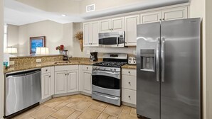 A modern kitchen with white cabinets, stainless steel appliances, and a granite countertop.