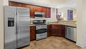 A modern kitchen with stainless steel appliances, wooden cabinets, and a granite countertop.