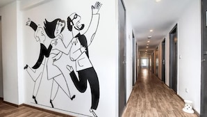 Een hal met een modern design, bestaande uit een lange gang met houten vloeren en een rij deuren aan één kant.