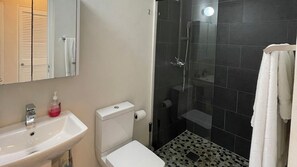 A bathroom with a sink, toilet, and shower. - Zinnia #7 - by ZenBreak (Fitts Village)