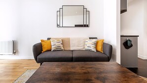 Ein modernes Wohnzimmer mit einer Couch, einem Couchtisch und einem an der Wand befestigten Spiegel.