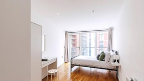 Ein Schlafzimmer mit einem Bett, einem Schreibtisch und einem Fenster mit Vorhängen.