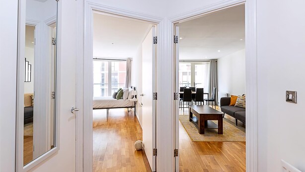 Eine moderne Wohnung mit Holzboden, einem Bett, einem Essbereich und einem Wohnzimmer.