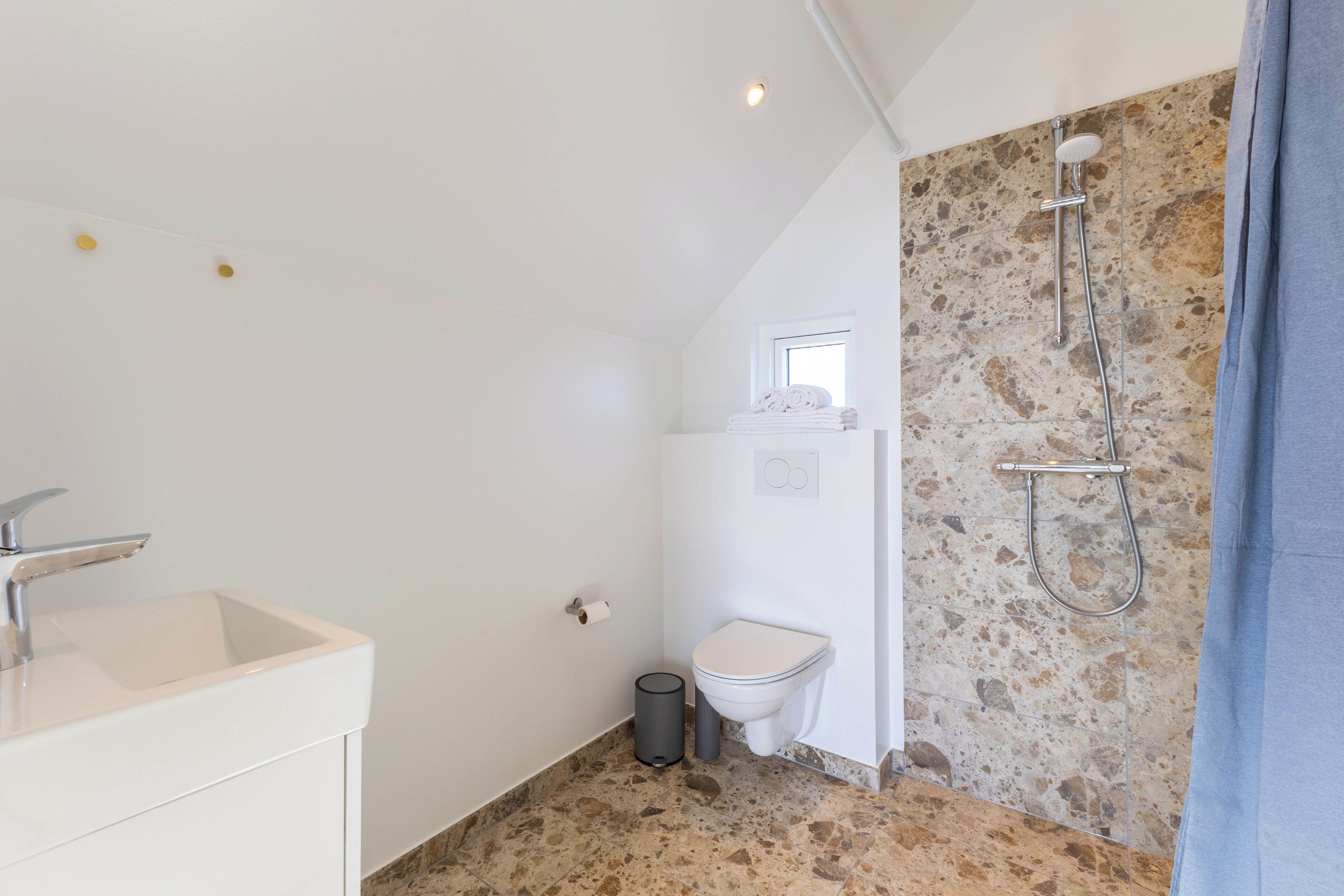 Un baño con lavamanos, inodoro y ducha blancos.