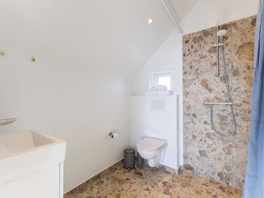 A bathroom with a white sink, toilet, and shower.