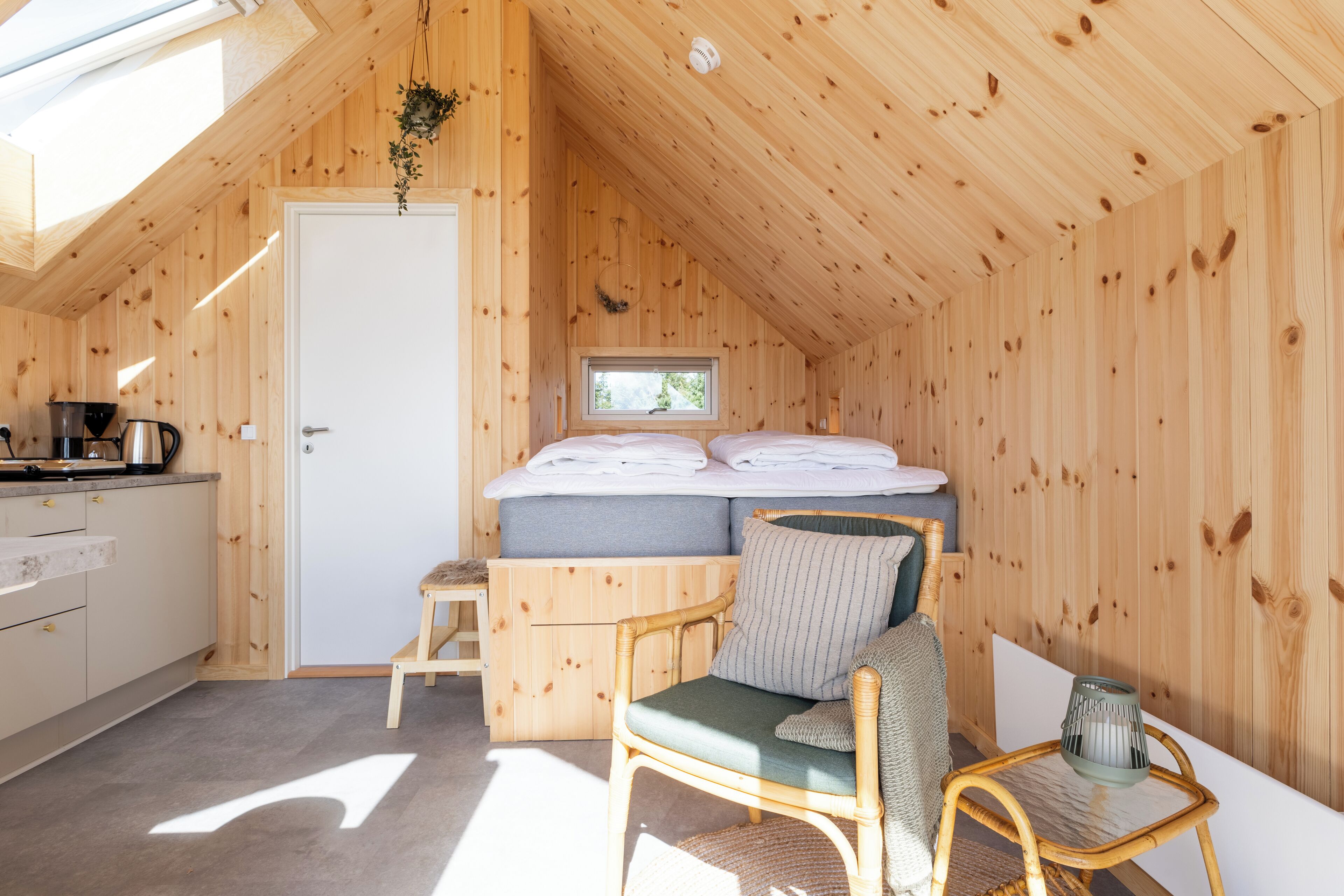 Ein gemütliches Holzhaus mit Schlafzimmer auf dem Dachboden, einer Küchenzeile und einem Essbereich.