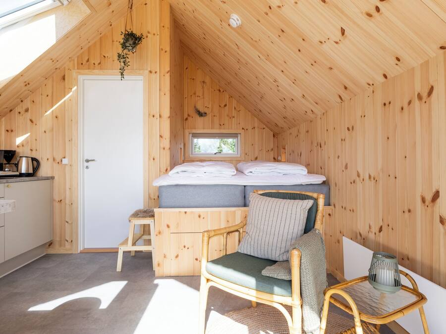 A cozy wooden cabin with a loft bedroom, a kitchenette, and a dining area.