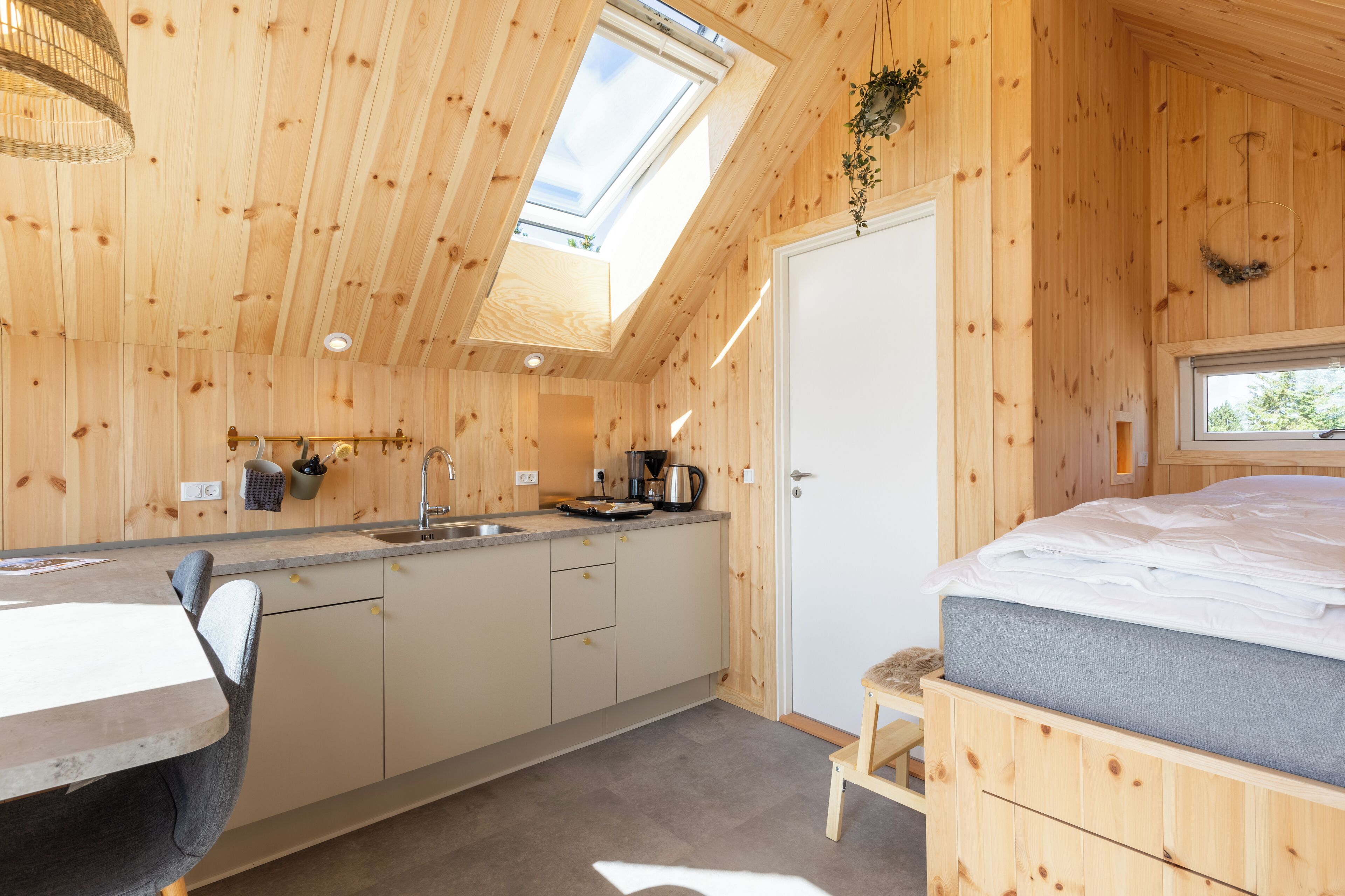 A wooden cabin with a kitchen, a dining area, and a bedroom.