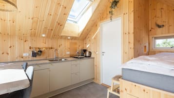 A wooden cabin with a kitchen, a dining area, and a bedroom.