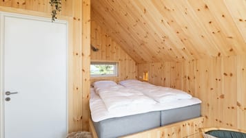 A wooden room with a bed, a window, and a door.