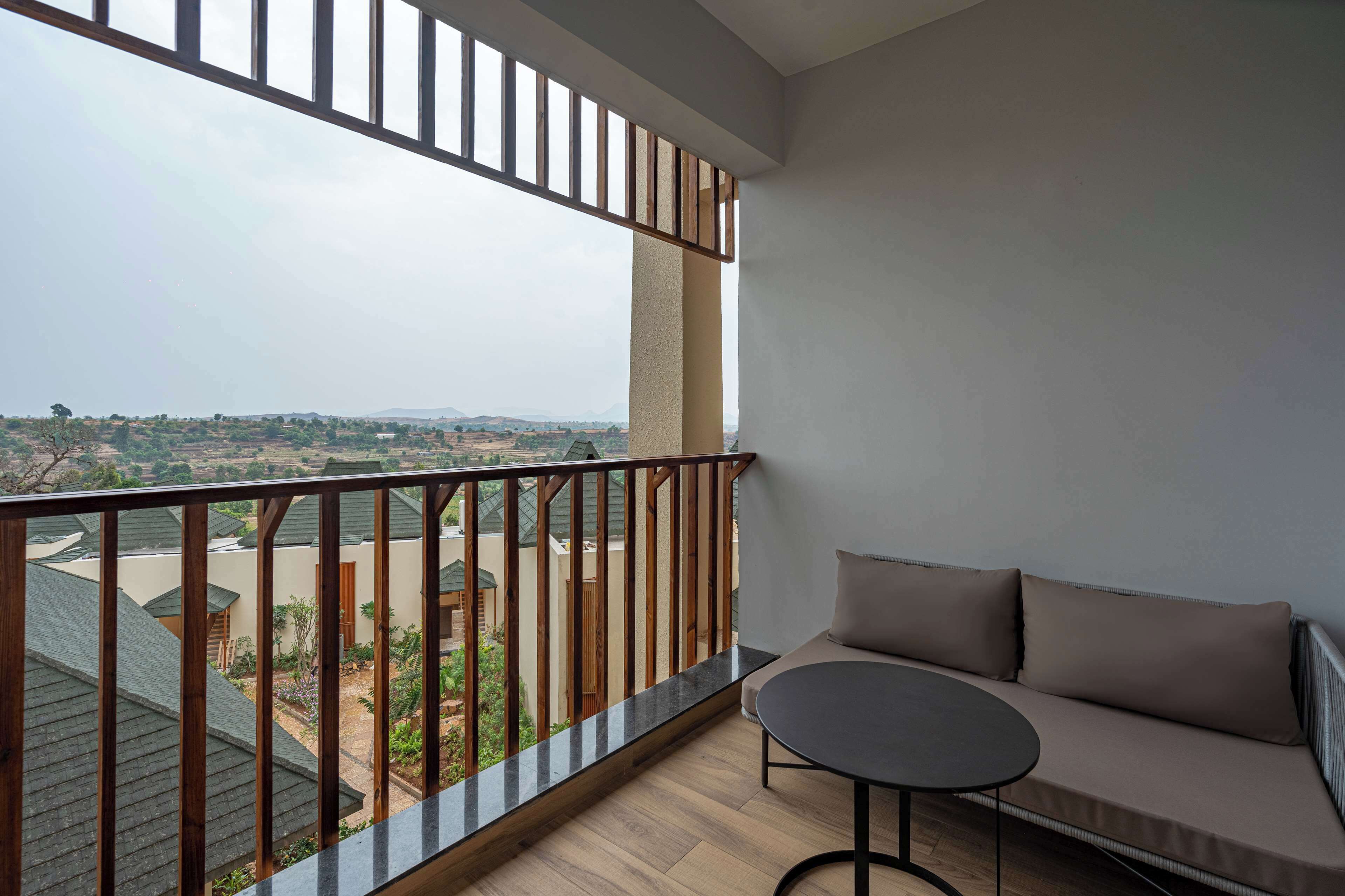 A balcony with a wooden railing, a sofa, and a round table.