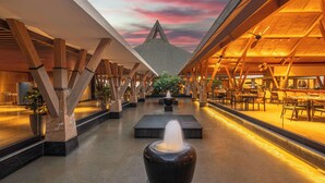 A spacious indoor area with a central water feature, wooden beams, and seating areas. - Radisson Resort Hatgad Saputara (Surgana)