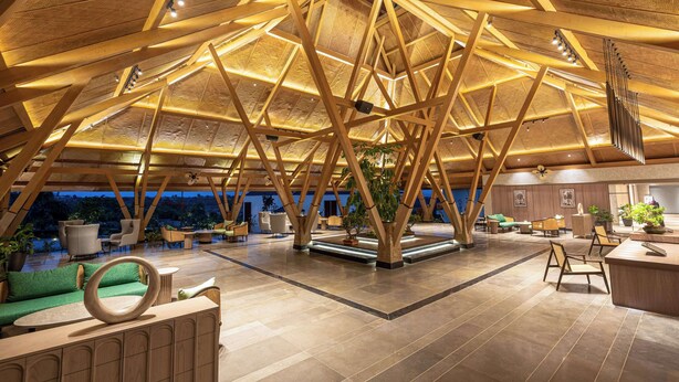 A spacious lobby with a high wooden ceiling, seating areas, and a central plant. - Radisson Resort Hatgad Saputara (Surgana)