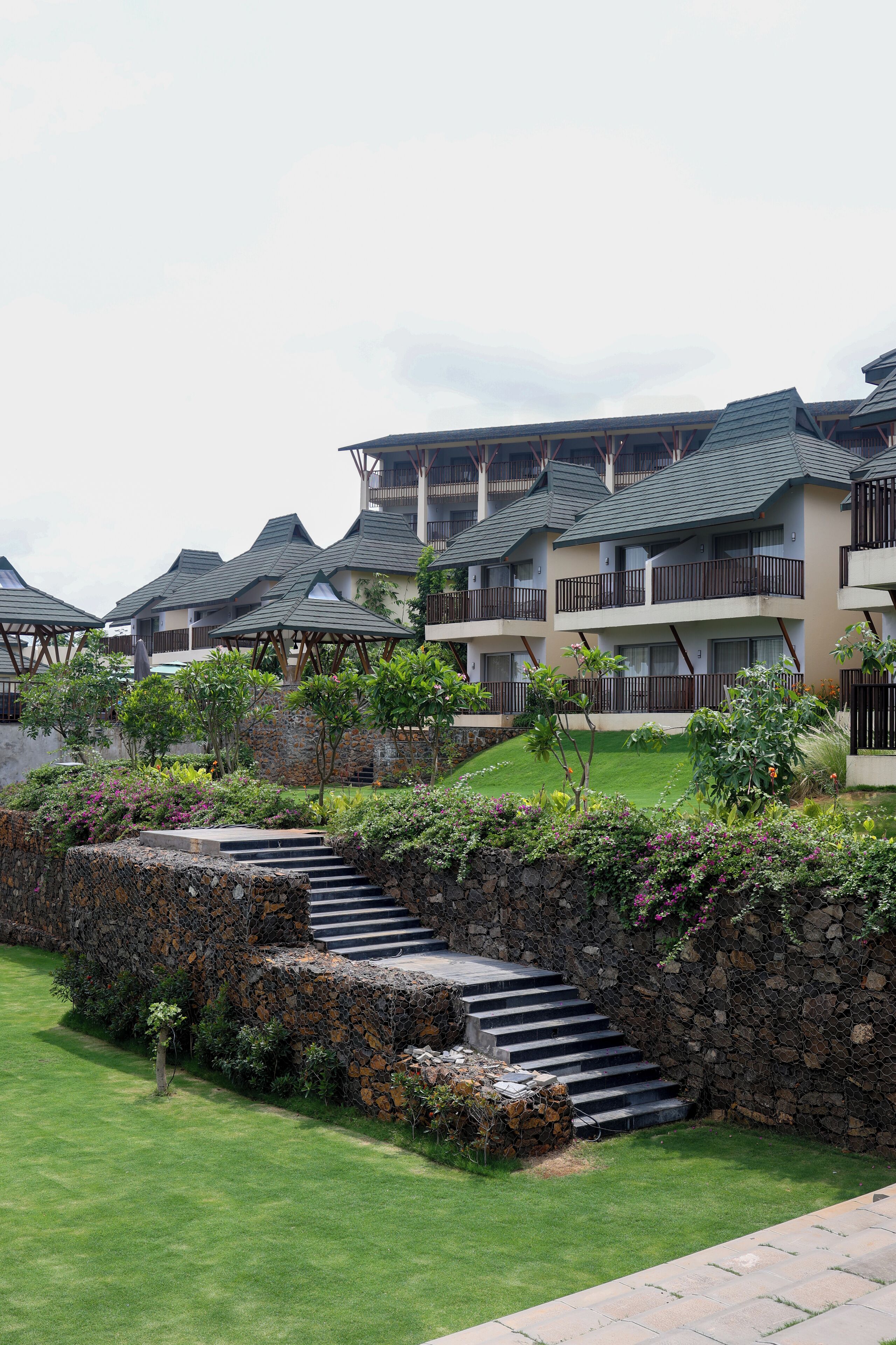 A resort with multiple buildings, stone walls, and a well-maintained lawn.
