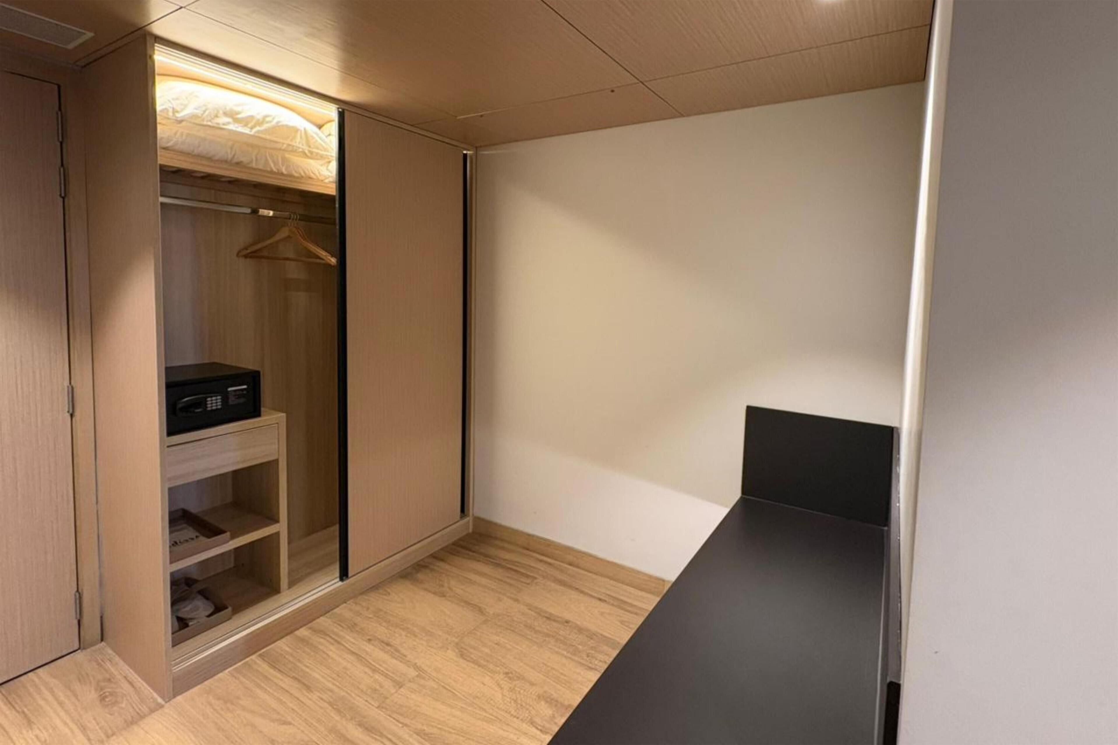 A compact room with a wardrobe, a small shelf with a microwave, and a black table.