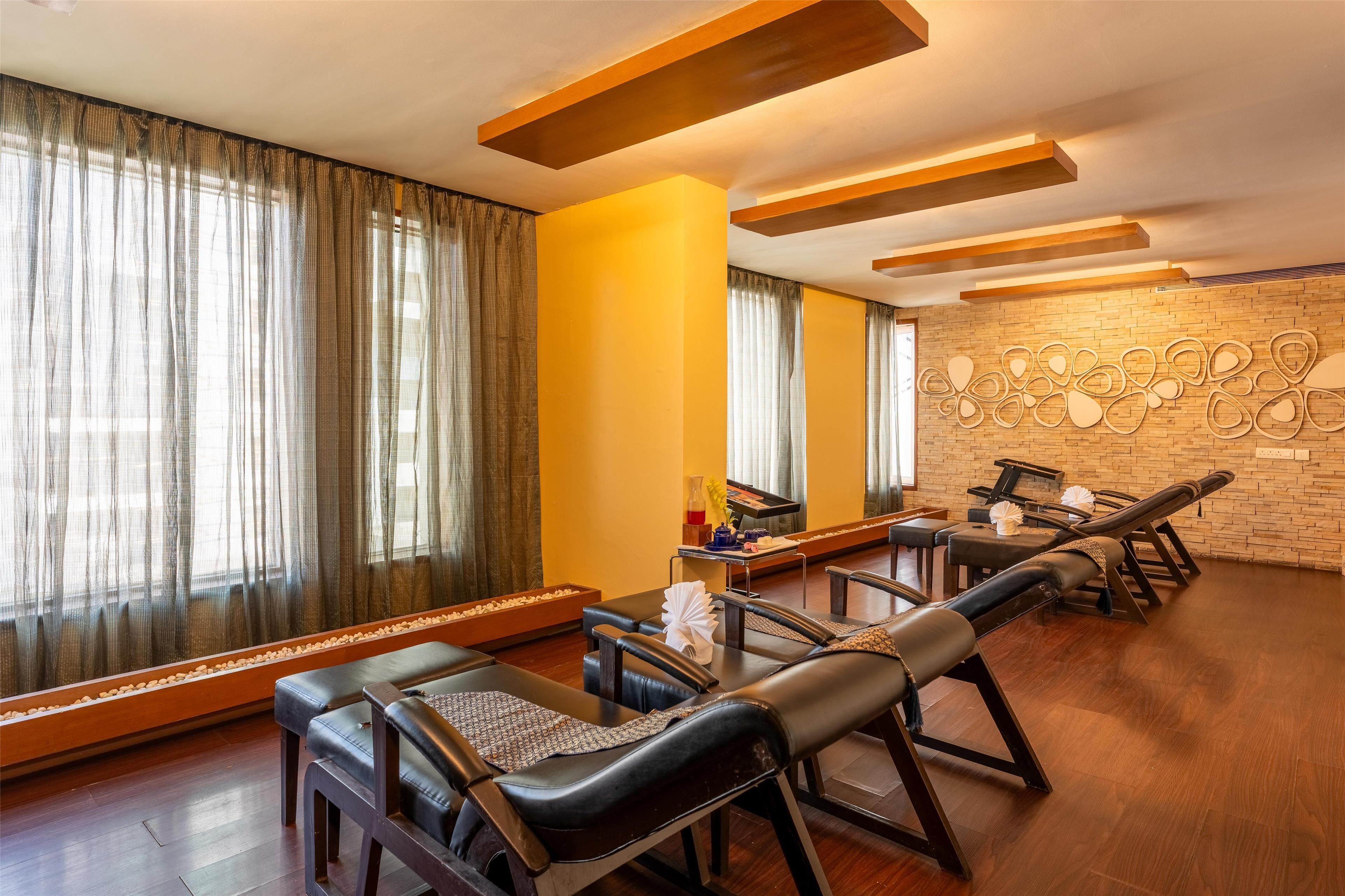 A room with massage chairs, a brick wall, and a large window with curtains.