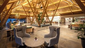 A spacious lobby with high wooden beams, comfortable seating, and a central plant. - Radisson Resort Hatgad Saputara (Surgana)