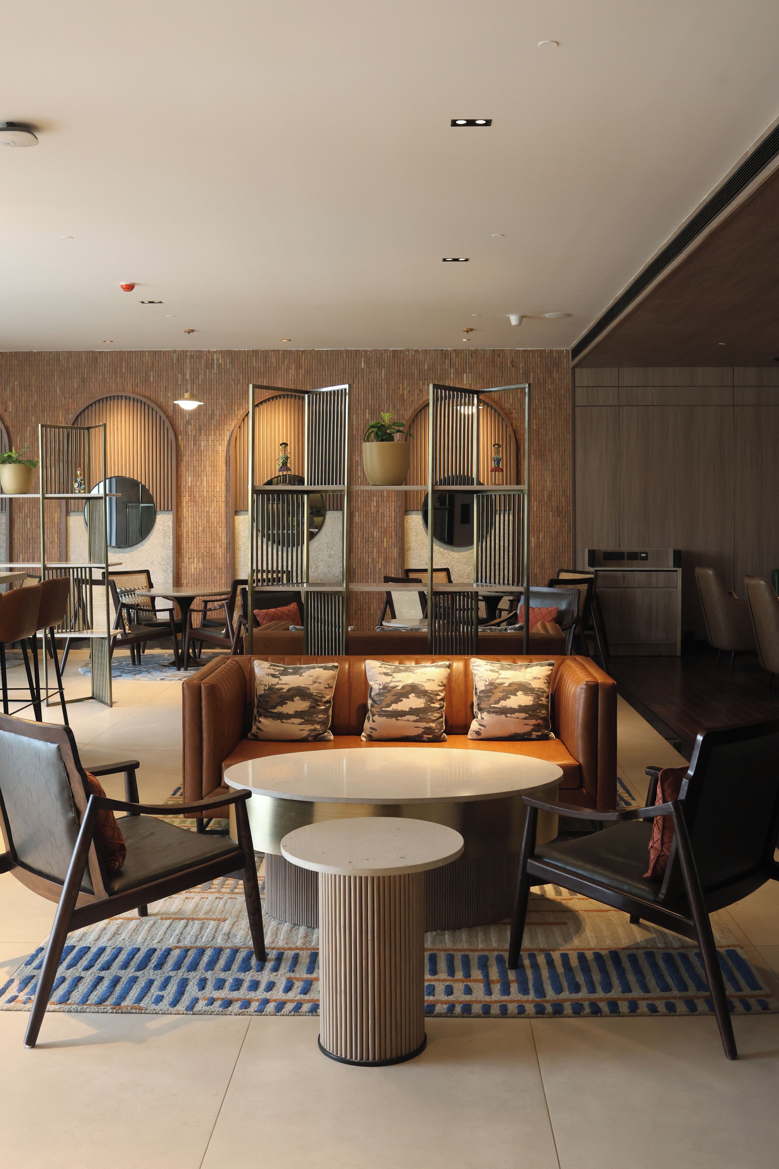 Un interior moderno con zona de estar, mesas y una pared decorativa con estanterías.