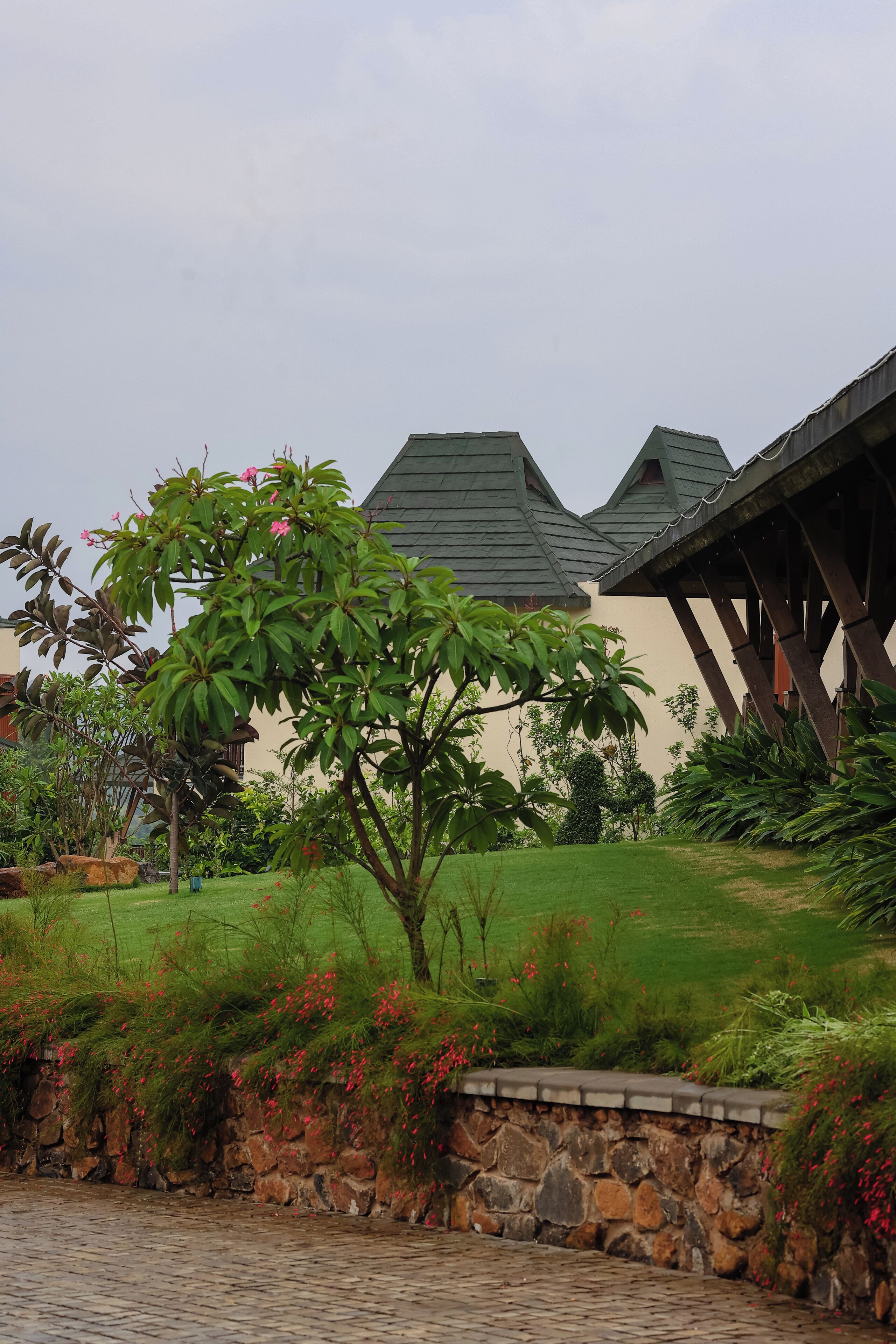 A stone wall, a tree, and a building with a green roof.