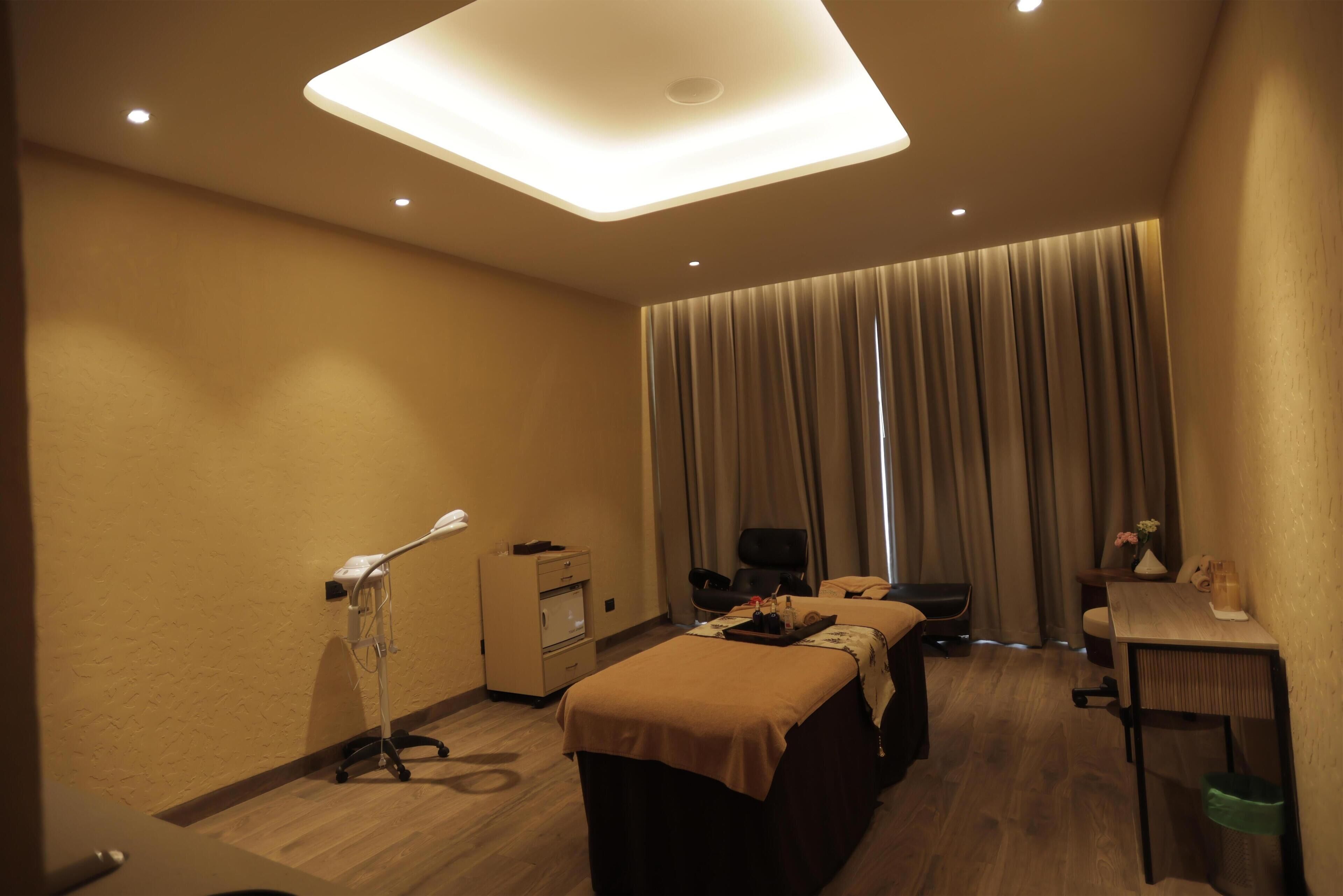Une chambre d’hôtel avec deux lits, un bureau, une chaise, une télévision et un fauteuil massant.