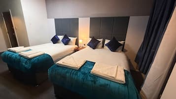 A hotel room with two beds, each with a headboard, a nightstand, and a lamp.